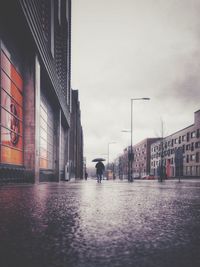 Man walking on wet street in city