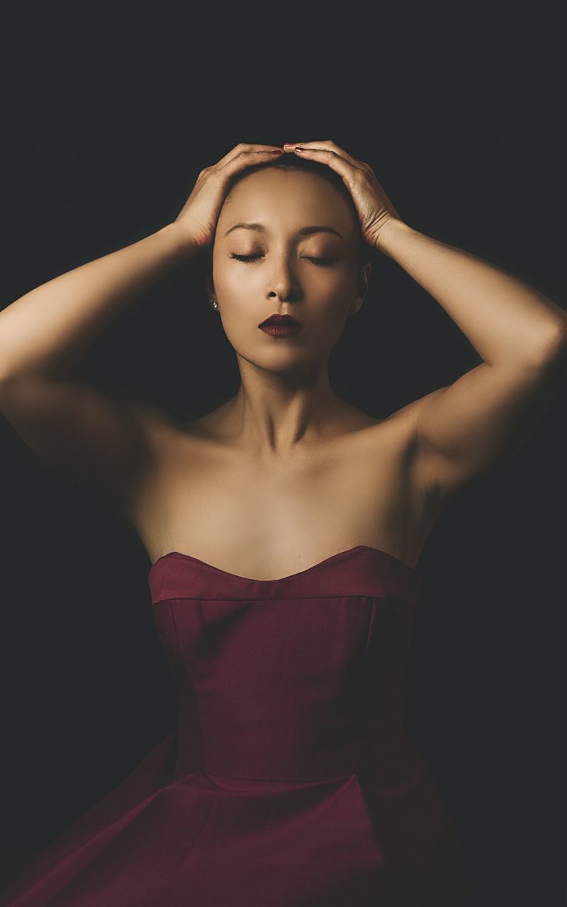 studio shot, eyes closed, young adult, black background, beautiful woman, front view, young women, hand in hair, one person, standing, fashion, night, real people, beauty, fashion model, indoors, close-up