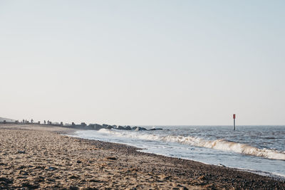 View of horsey gap beach, norfolk, uk, at sunset, silhouettes of unidentifiable people on horizon.