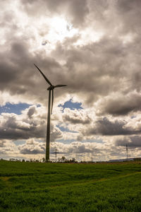 Low angle view of windmill on field against sky