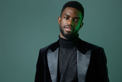 Portrait of young man standing against black background