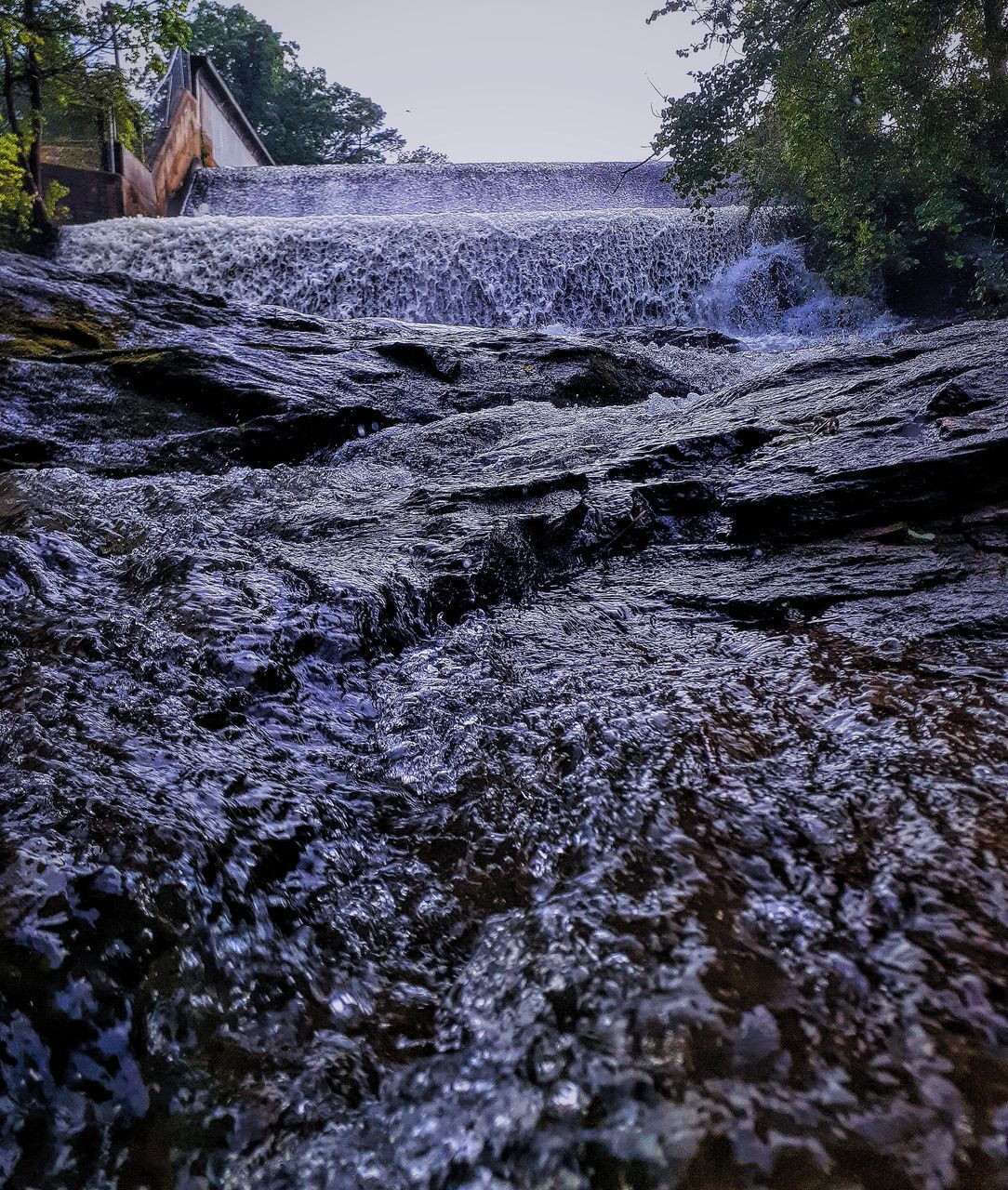 SURFACE LEVEL OF WATER FLOWING THROUGH ROCKS IN SUNLIGHT