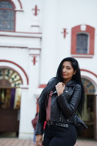 Young woman standing with umbrella in front of building