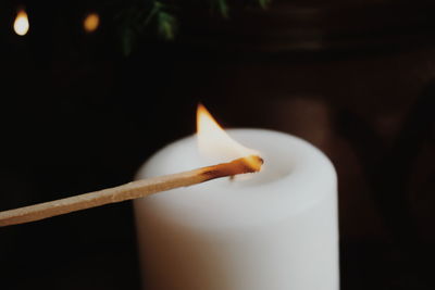 Close-up of illuminated matchstick with candle