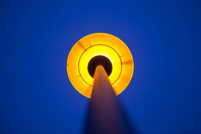 Low angle view of illuminated lamp against blue sky