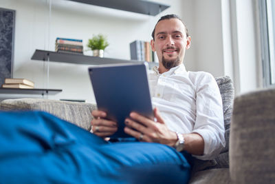 Man using mobile phone while sitting on sofa at home
