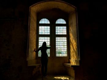 Silhouette woman standing by window in building