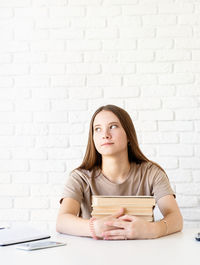 Portrait of beautiful young woman against wall