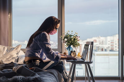 Side view of man using mobile phone while sitting on table