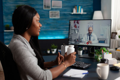 Side view of young woman using laptop at table