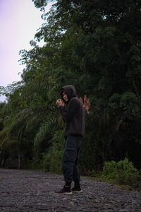 Side view of young man standing against plants