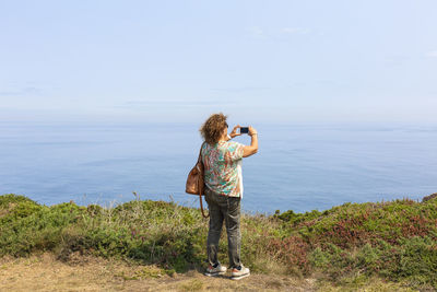 Back view of woman photographing sea