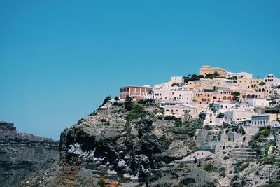 Low angle view of residential district on mountain against clear blue sky