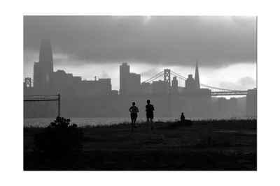 Silhouette people standing by cityscape against sky