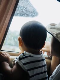 Rear view of woman looking through window
