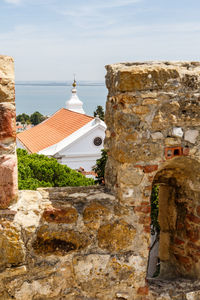 Stone wall by historic building against sky