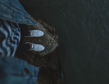 Low section of woman standing by water
