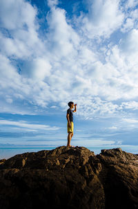 Full length of man standing on rock against sky