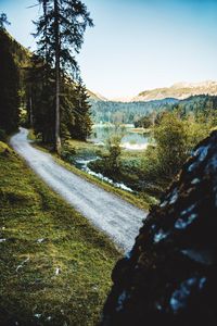 Road amidst trees and landscape against sky