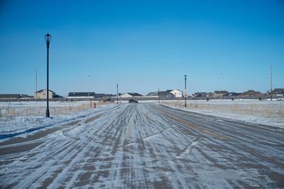 Snow covered road against clear blue sky