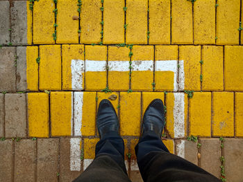 Low section of man standing on yellow street