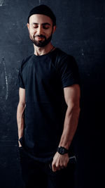 Portrait of young man standing against wall