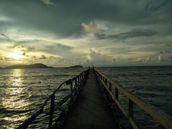 Pier over sea against sky during sunset