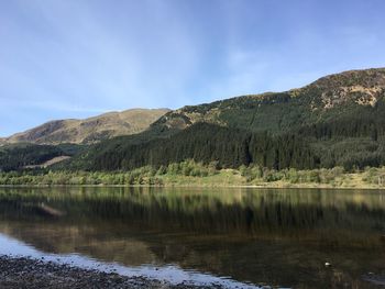 Scenic view of lake by mountains against sky