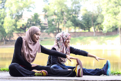 Sisters wearing hijab while exercising by lake at park