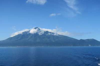 Scenic view of sea and mountains against blue sky