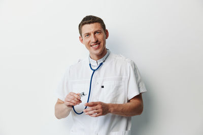 Portrait of doctor standing against white background