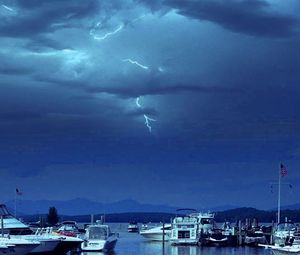 Boats in sea against cloudy sky