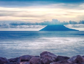 Scenic view of sea against cloudy sky at sunset