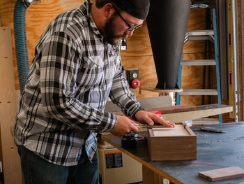 A carpenter cutting off extra wood off the box he is building