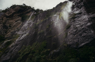 Low angle view of waterfall on rocks