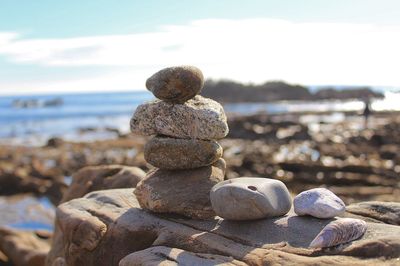 Stack of pebbles at beach against sky