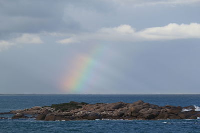 Scenic view of rainbow over sea against sky