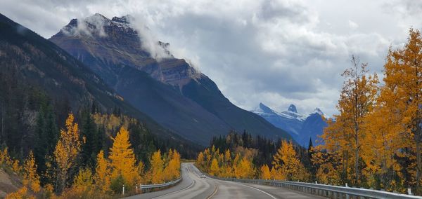 Road amidst trees and mountains against sky