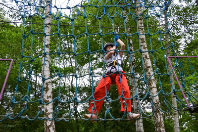 Adventure climbing high wire park - people on course in mountain helmet and safety equipment.