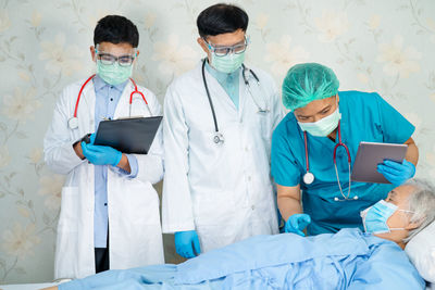 Doctor wearing mask examining senior woman at hospital