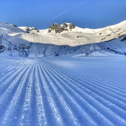 Snow covered landscape against blue sky