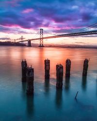 Oakland bay bridge against cloudy sky during sunset