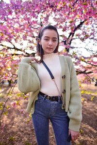 Portrait of beautiful young woman standing by flowering tree