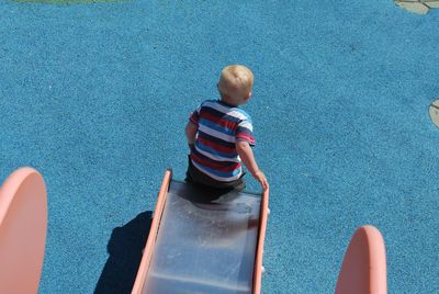 High angle view of baby boy playing on slide at playground