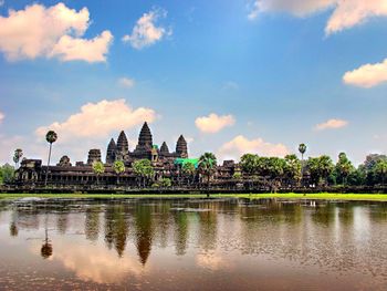 Panoramic view of temple by lake against sky