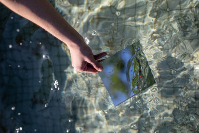 Cropped hand of woman holding glass in swimming pool