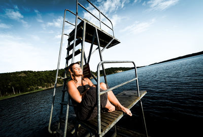 Portrait of young woman in boat sailing on sea against sky