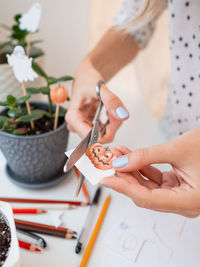 Woman decorates flower pots with stickers for halloween. hand drawn pumpkin, ghosts and flags.