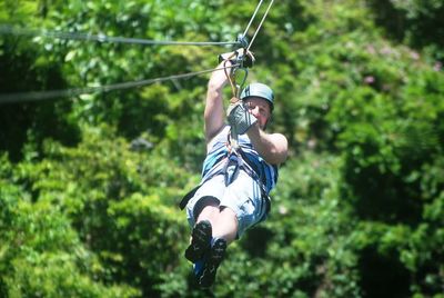 Man zip lining at forest