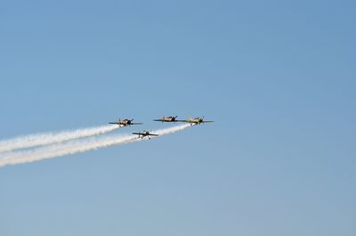 Low angle view of airplane flying against clear blue sky